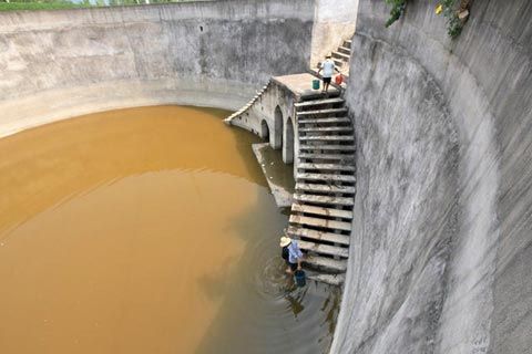 7月31日,湖北省郧县徐家村村民从基本干涸的池塘里挑水。(图片来源于新华网)